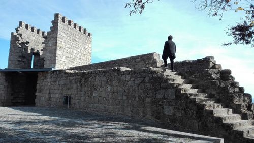 Rear view of man by historic building against sky