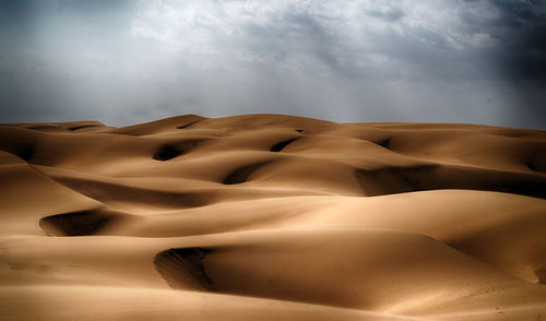 Sand dunes in desert against sky