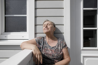 Relaxed senior woman sitting on porch in sunshine