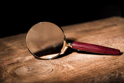 Close up single magnifying glass with black handle, leaning on the wooden table at the office.