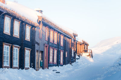 Snow covered buildings against clear sky