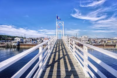 Footbridge over sea against blue sky