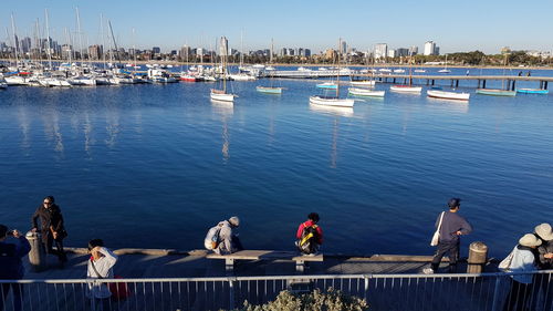 People on pier by river against sky