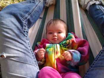 Low section of man with baby relaxing in hammock