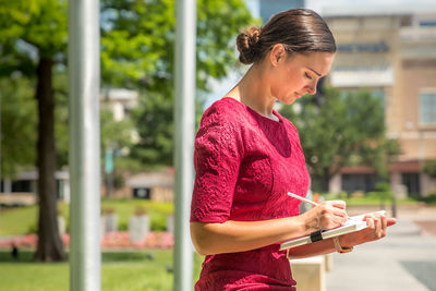 Young woman looking away while standing on mobile phone