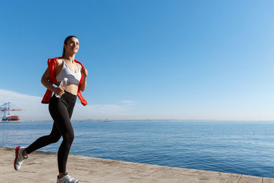 Full length of young woman in sea against sky