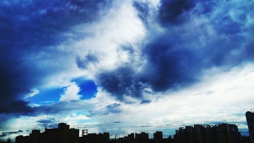 Low angle view of cityscape against cloudy sky