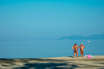 Rear view of people on beach against sky