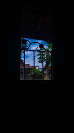 Silhouette trees and building seen through window