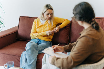Young woman using mobile phone while sitting on sofa at home