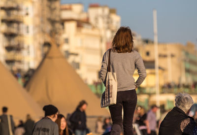 Rear view of woman walking against buildings in city