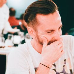 Close-up of man laughing while covering mouth in restaurant