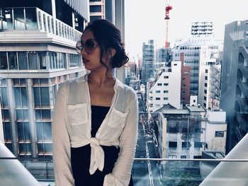 Young woman looking through glass window in city