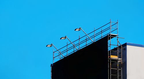 Low angle view of electricity pylon against clear blue sky