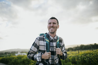 Happy mature man with backpack hiking under sky