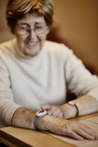 Senior woman pressing emergency button on wrist over table at home
