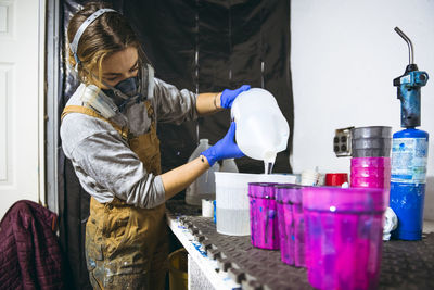 Female resin artist mixing and pouring with respirator mask