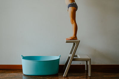 Low section of girl standing on chair at home