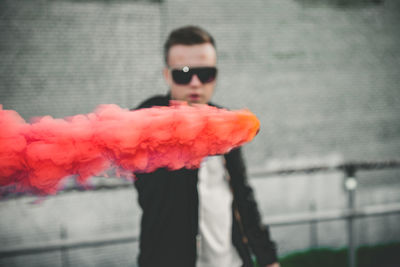 Close-up portrait of man holding smoke bomb