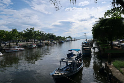 Sailboats moored on river against sky