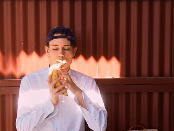 Close-up of young man holding bananas against corrugated iron