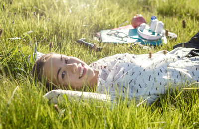 Portrait of young woman while lying on grass at park