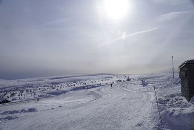Scenic view of snow covered landscape against bright sun