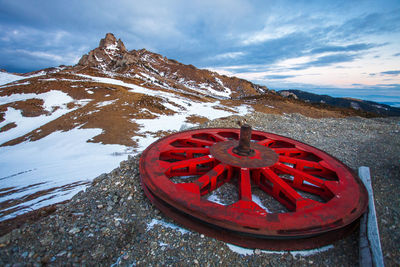 Close-up of red wheel against snowcapped mountain