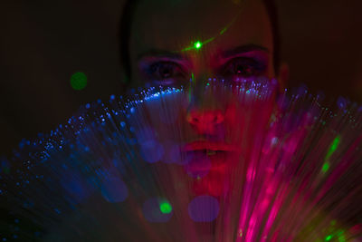 Portrait of beautiful young woman against illuminated background