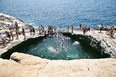 High angle view of people enjoying at rock formation by sea