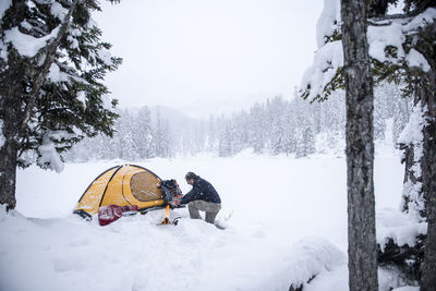 Senior man camping in snow-covered landscape