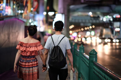 Rear view of people standing on street at night