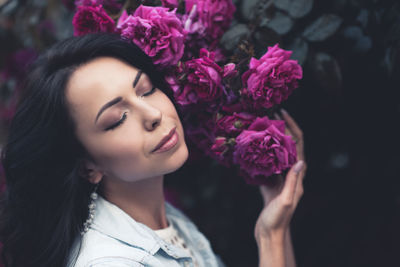 Dark portrait of young woman 24-26 year old posing outdoor with closed eyes hold bloom roses outdoor