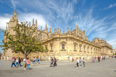 People walking outside historic cathedral against sky