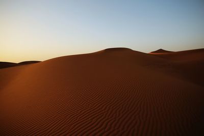 Scenic view of desert against clear sky during sunset