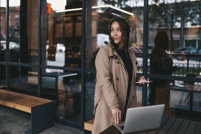 Young woman using phone while standing on table