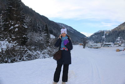 Full length of woman talking over phone while standing in snow