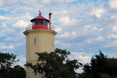 Low angle view of lighthouse by building against sky