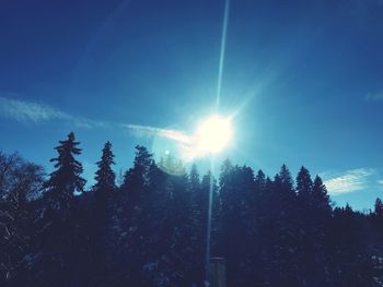 Low angle view of silhouette trees against blue sky