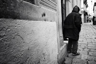 Rear view of man walking on cobblestone street