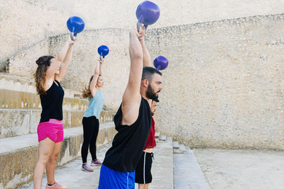 Athletes lifting a kettelbell crossfit weights in an urban enviroment.