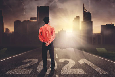 Rear view of man standing on road in city