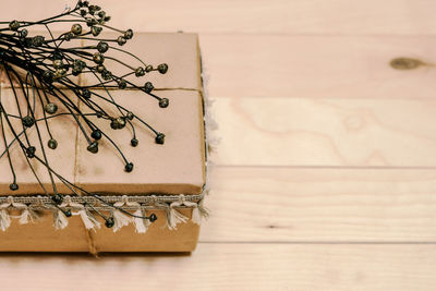 High angle view of gift box with dried plant on wooden table