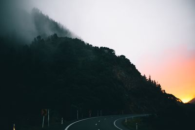 Tree mountain by empty road against sky