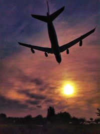 Silhouette airplane flying against sky during sunset