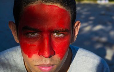 Close-up portrait of young man with red face paint