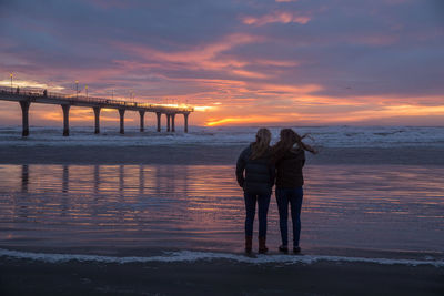 Silhouette of people on beach at sunset