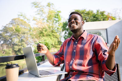 Young man using mobile phone while sitting on table