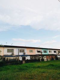 Abandoned house on field by buildings against sky