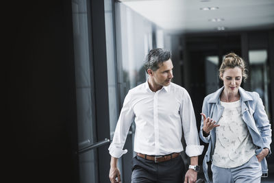 Businesswoman and businessman talking in office passageway